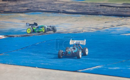 Foto de Mérida, España - 28 de enero de 2024: Extremadura 1 / 8tt gas Championship RC Car. Coches haciendo una curva sobre césped azul - Imagen libre de derechos