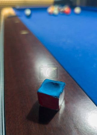 Gebrauchter Kreidewürfel auf Schiene gelegt. Billardspiel mit acht Bällen an sechs blauen Pocket-Tischen