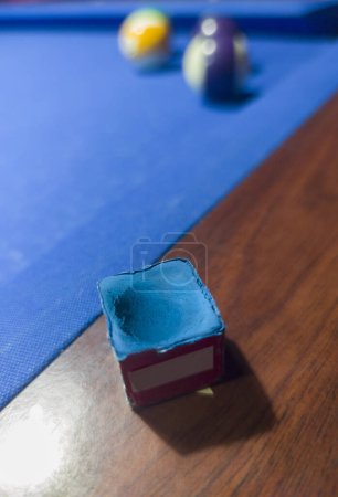 Gebrauchter Kreidewürfel auf Schiene gelegt. Billardspiel mit acht Bällen an sechs blauen Pocket-Tischen