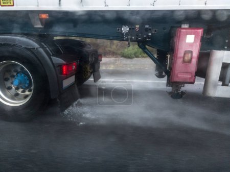 Ruedas de camiones salpicando agua en la carretera. Peligros que conducen cerca de camiones