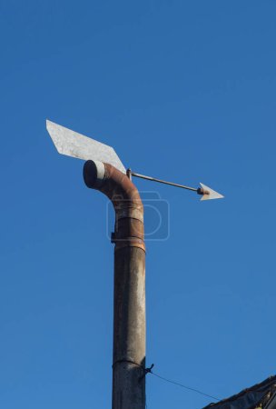 Téléchargez les photos : Capuchon de cheminée directionnel à vent domestique équipé d'une flèche. Fond bleu ciel - en image libre de droit