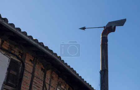 Téléchargez les photos : Capuchon de cheminée directionnel à vent domestique équipé d'une flèche. Fond bleu ciel - en image libre de droit