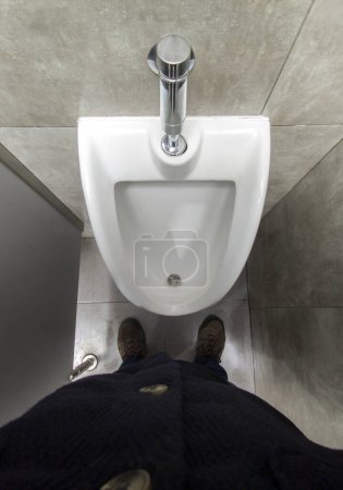 Hombre maduro frente a un urinario. Vista aérea