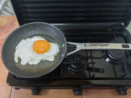 Big goose egg frying in a pan on a gas stove. Overhead view