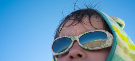 3-jähriger Junge geschützt mit Sonnenbrille am Strand. Gesundheitskonzept für Kinder