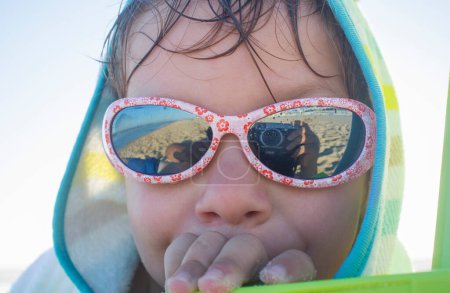 Niño de 3 años protegido con gafas de sol en la playa. Concepto de salud ocular infantil