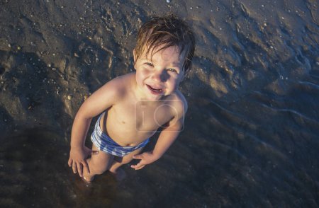 3 years baby boy at the beach with unprotected eyes and skin. Children health concept on summer season