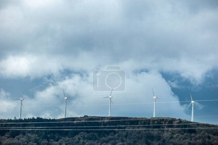 Turbinas eólicas en la cima de las colinas. Líneas eléctricas en primer plano