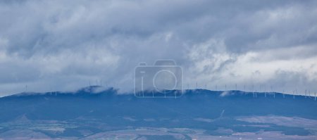 Photo for Wind park on the top of the hills. Clouds partially hide the wind turbines - Royalty Free Image