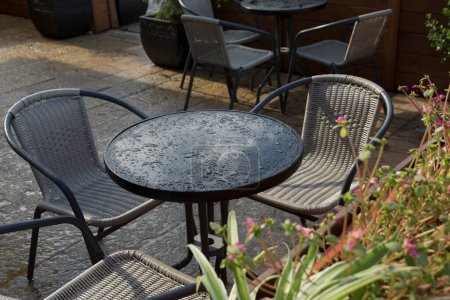 Foto de Gotas después de la lluvia en una mesa redonda y sillas de mimbre en el patio - Imagen libre de derechos