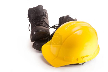 Foto de Casco amarillo y botas para trabajar en obras e instalaciones de producción - Imagen libre de derechos