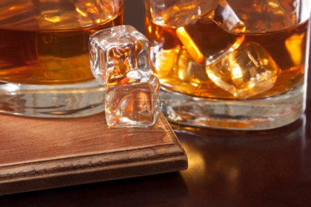 Foto de Cubos de hielo en vasos con whisky y en el exterior sobre una mesa lacada - Imagen libre de derechos