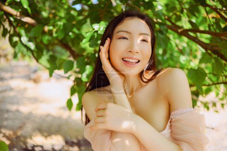 Photo for Close up outdoor portrait Beautiful young Chinese Asian woman perfect skin posing outside sunny summer day green foliage. Natural facial treatment. Cosmetology, skin care and spa. Fragnance concept - Royalty Free Image