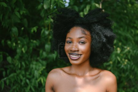 Nahaufnahme Porträt Schöne junge Afroamerikanerin Schwarze Frau perfekte weiße Zähne lächeln draußen, sonnigen Sommertag grünes Laub. Gesichtsbehandlung. Kosmetologie, Hautpflege und Wellness