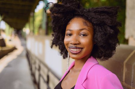 Mode im Freien Street Style Porträt der schönen jungen Afroamerikanerin posiert draußen auf städtischen Stadtlandschaft Sommertag trägt rosa Jacke. Attraktive schwarze Frauen, Diversitätskonzept