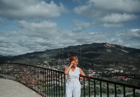 Reife Touristin auf der Aussichtsplattform der antiken Klosterruinen in der Nähe der Stadt Mzcheta, Georgien. Rentner Sommerurlaub, aktives Lebensstil-Konzept. 