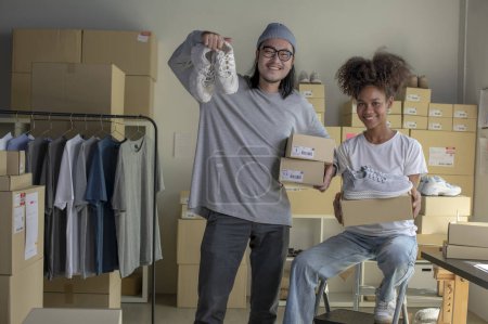 Téléchargez les photos : Confident mixed race young couple of Asian man and african-american woman retail seller, entrepreneur, online store drop shipping small business owner looking at camera in delivery shipping warehouse - en image libre de droit