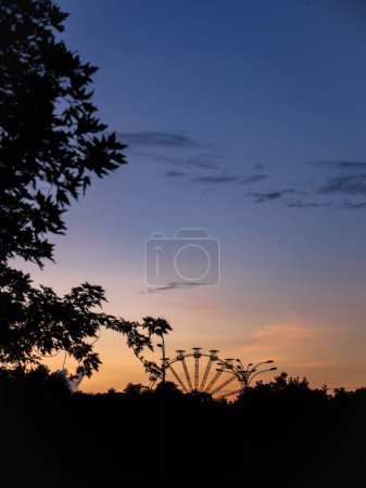 Big and high panoramic observation wheel on the horizon with colorful sunset sky in the background in Kyiv, Ukraine.