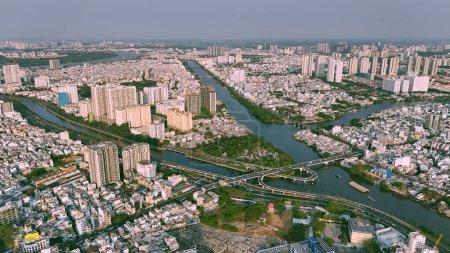 Aerial view from drone of Ho Chi Minh, big Asian city with row of crowded house, Nhieu Loc Thi Nghe canal, Y bridge cross water, vehicle traffic on road, level 4 house slum