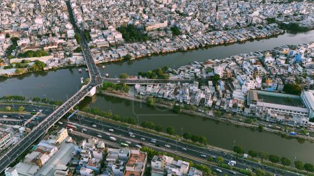 Vue aérienne depuis le drone de Ho Chi Minh, grande ville asiatique avec rangée de maisons bondées, canal Nhieu Loc Thi Nghe, pont Y traversant l'eau, circulation automobile sur la route, bidonville de niveau 4