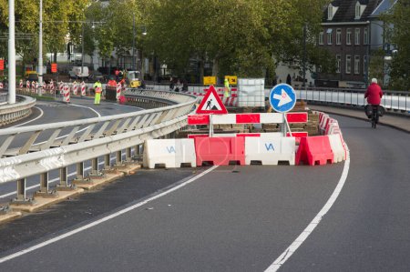 Foto de Arnhem, Países Bajos - 4 de noviembre de 2022: Lugar de trabajo cerrado con retenes para obras viales con trabajadores de la carretera - Imagen libre de derechos