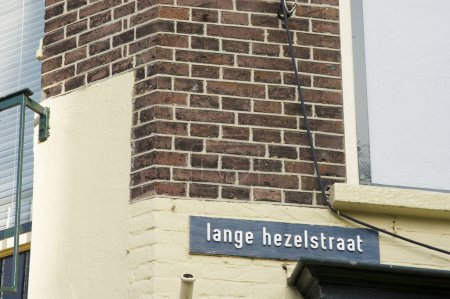 Foto de Blue street name sign of Lange Hezelstraat on a brown stone wall in Nijmegen in the Netherlands - Imagen libre de derechos