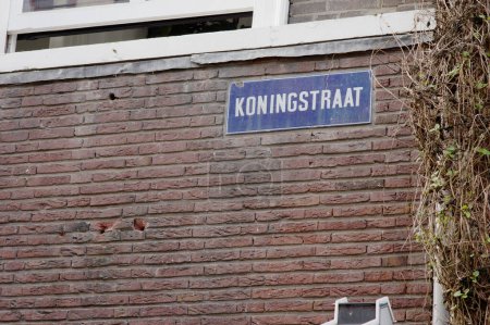 Blue street name sign of Koningstraat on a brick stone wall  in Arnhem in the Netherlands