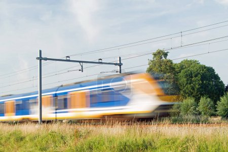Téléchargez les photos : Le train Sprinter passe à grande vitesse, flou par le mouvement à Arnhem aux Pays-Bas - en image libre de droit