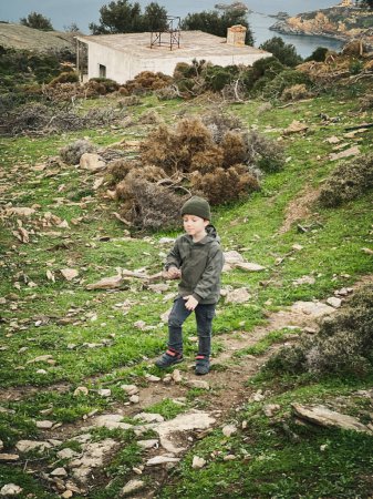 Foto de Longitud completa de niño elemental caucásico con ropa de abrigo senderismo en la montaña mientras disfruta de vacaciones - Imagen libre de derechos