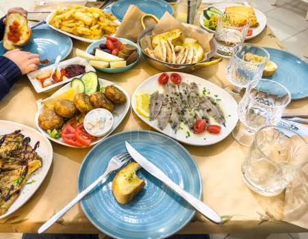 Foto de Alto ángulo manos recortadas de niño con varios alimentos en platos servidos en la mesa de comedor en el restaurante - Imagen libre de derechos