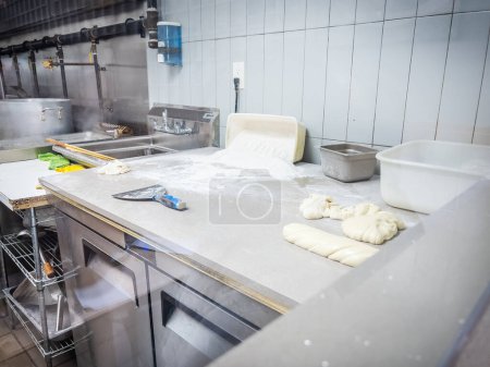 Foto de Masa y harina derramadas en encimera blanca contra pared de azulejos en cocina comercial - Imagen libre de derechos