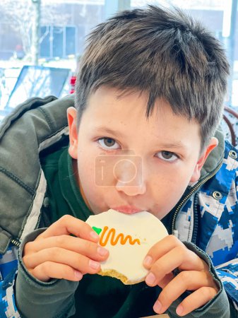 Foto de Retrato de cerca del adolescente caucásico con chaqueta de invierno comiendo galletas en el restaurante durante el invierno - Imagen libre de derechos