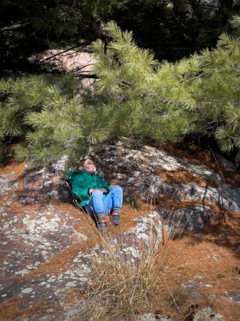 Foto de Vista de ángulo alto del niño caucásico durmiendo en la formación de rocas bajo sombra de árbol en el bosque durante las vacaciones - Imagen libre de derechos