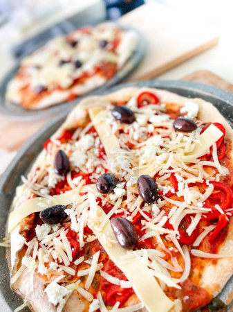 Foto de Primer plano en ángulo alto de pizzas frescas decoradas con queso y aceitunas servidas en plato sobre mesa - Imagen libre de derechos