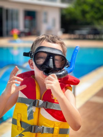 Foto de Retrato de chico alegre caucásico usando snorkel y chaleco salvavidas disfrutando de fin de semana en resort turístico - Imagen libre de derechos