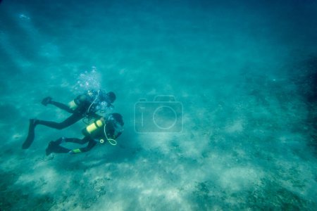 Foto de Padre caucásico con su hijo buceando y explorando juntos bajo aguas profundas en el mar azul durante las vacaciones - Imagen libre de derechos