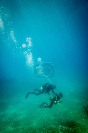 Foto de Hombre e hijo caucásicos explorando el océano juntos mientras bucean bajo aguas profundas en el mar azul durante las vacaciones - Imagen libre de derechos