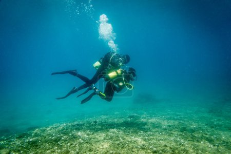 Foto de Padre caucásico con su hijo buceando y explorando el océano juntos bajo aguas profundas en el mar azul durante las vacaciones - Imagen libre de derechos
