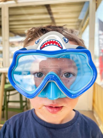 Foto de Retrato de cerca del lindo chico con ojos grises usando gafas de natación en el complejo turístico mientras disfruta del fin de semana - Imagen libre de derechos