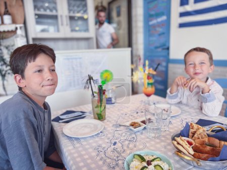 Foto de Lindos hermanos caucásicos sonriendo mientras almorzan juntos en la mesa en el restaurante mientras disfrutan del fin de semana - Imagen libre de derechos