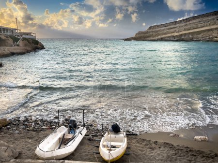 Foto de Barcos amarrados en la orilla y vista panorámica de las olas salpicando en el paisaje marino contra el cielo nublado - Imagen libre de derechos