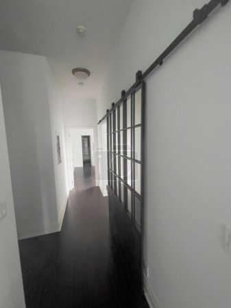 Foto de Partición de pantalla deslizante por pared blanca y perspectiva decreciente del corredor en apartamento moderno - Imagen libre de derechos