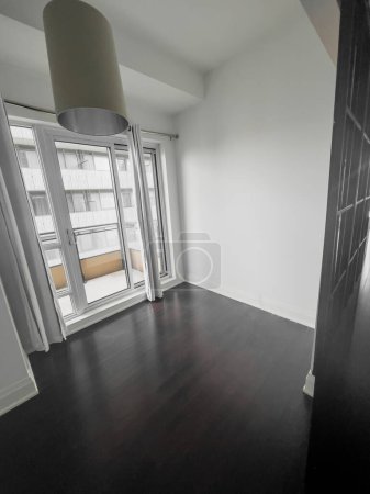 Foto de Puerta corredera en balcón y luz colgante colgando en el techo en la sala de estar vacía en la nueva casa - Imagen libre de derechos
