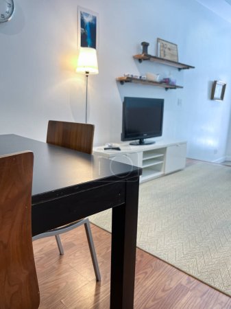 Foto de Decores lugares sobre la televisión por la lámpara de pie iluminada y mesa de comedor dispuestos en la sala de estar moderna en el nuevo apartamento - Imagen libre de derechos