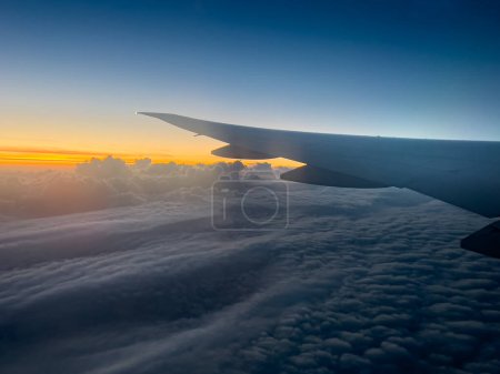 Foto de Imagen recortada del avión volando sobre la vista panorámica del paisaje nuboso esponjoso durante la puesta del sol - Imagen libre de derechos