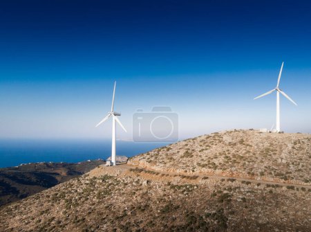 Foto de Turbinas eólicas en la cima de la montaña y vista panorámica del paisaje contra el cielo azul durante el día soleado - Imagen libre de derechos