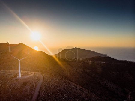 Foto de Turbinas eólicas en la montaña contra el cielo y vista panorámica de siluetas contra el sol brillante durante la puesta del sol - Imagen libre de derechos