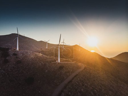 Foto de Vista tranquila de las montañas con aerogeneradores en rango contra el sol en el cielo durante el atardecer - Imagen libre de derechos