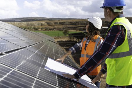 Foto de Ingeniero inspeccionar la instalación de paneles solares instalado comprobar con plano en el campo, con la grabación de datos de inspección en la PC. - Imagen libre de derechos