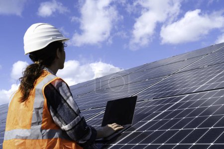 Téléchargez les photos : Jeune ingénieur inspecter l'installation de panneaux solaires installés vérifier avec le plan sur le terrain, avec l'enregistrement des données d'inspection sur PC. - en image libre de droit